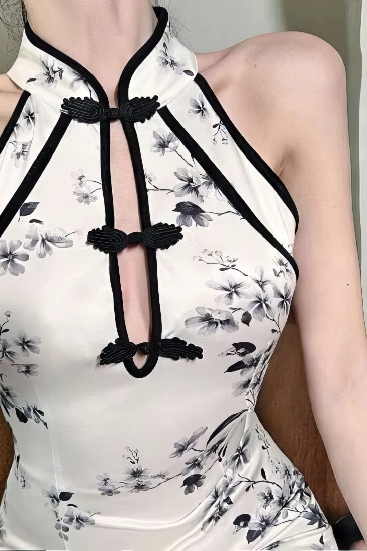 Detalle del cheongsam mini blanco con motivos florales en tinta china, cuello halter y sin mangas, mostrando el cierre tradicional de nudos chinos en negro