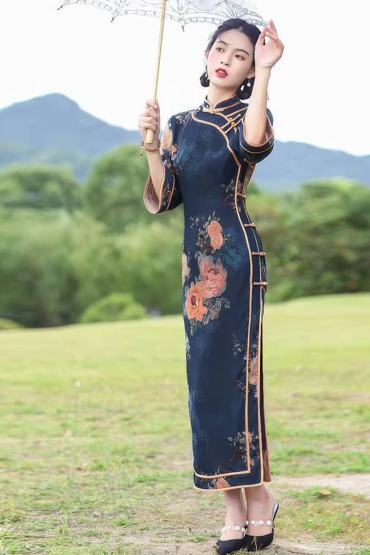 Qipao largo azul oscuro con motivos florales vintage en tonos naranjas, mangas tres cuartos y cuello mandarin, vista frontal completa en exterior
