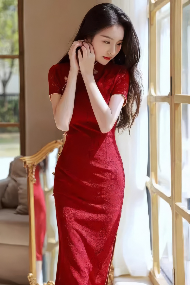 Qipao largo rojo burdeos de encaje con cuello mandarin y mangas cortas visto de frente junto a ventana