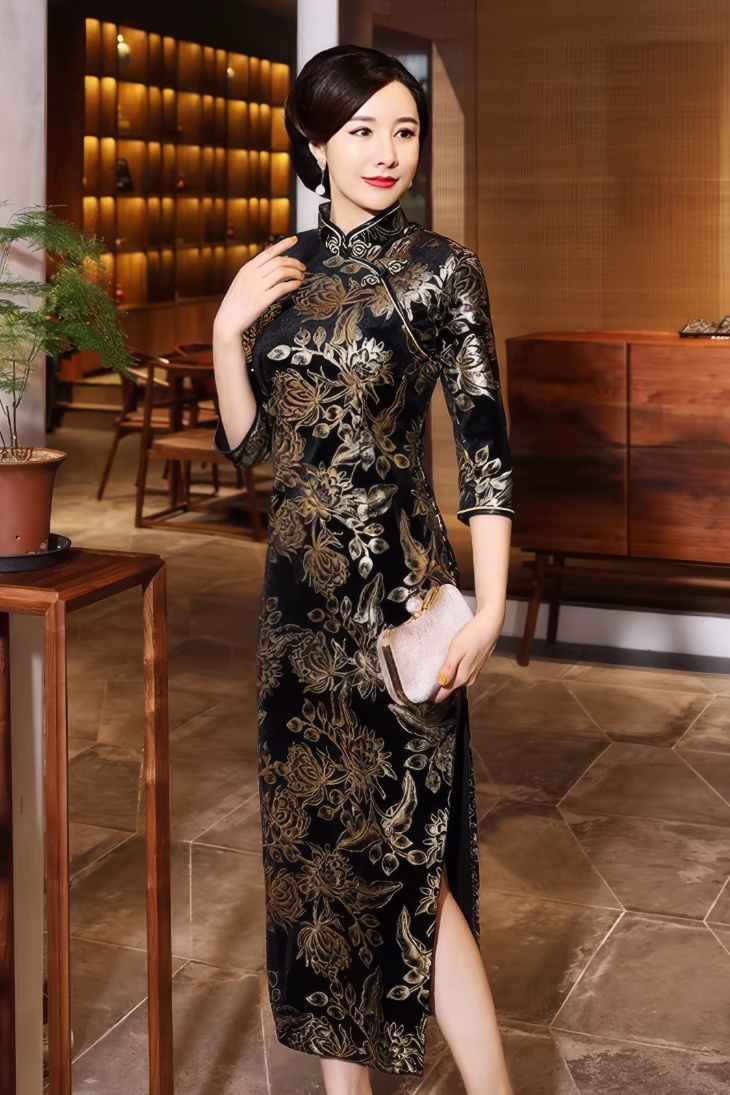 Qipao largo de terciopelo negro con motivos florales dorados, mangas tres cuartos y cuello mandarin, vista lateral con abertura en la falda
